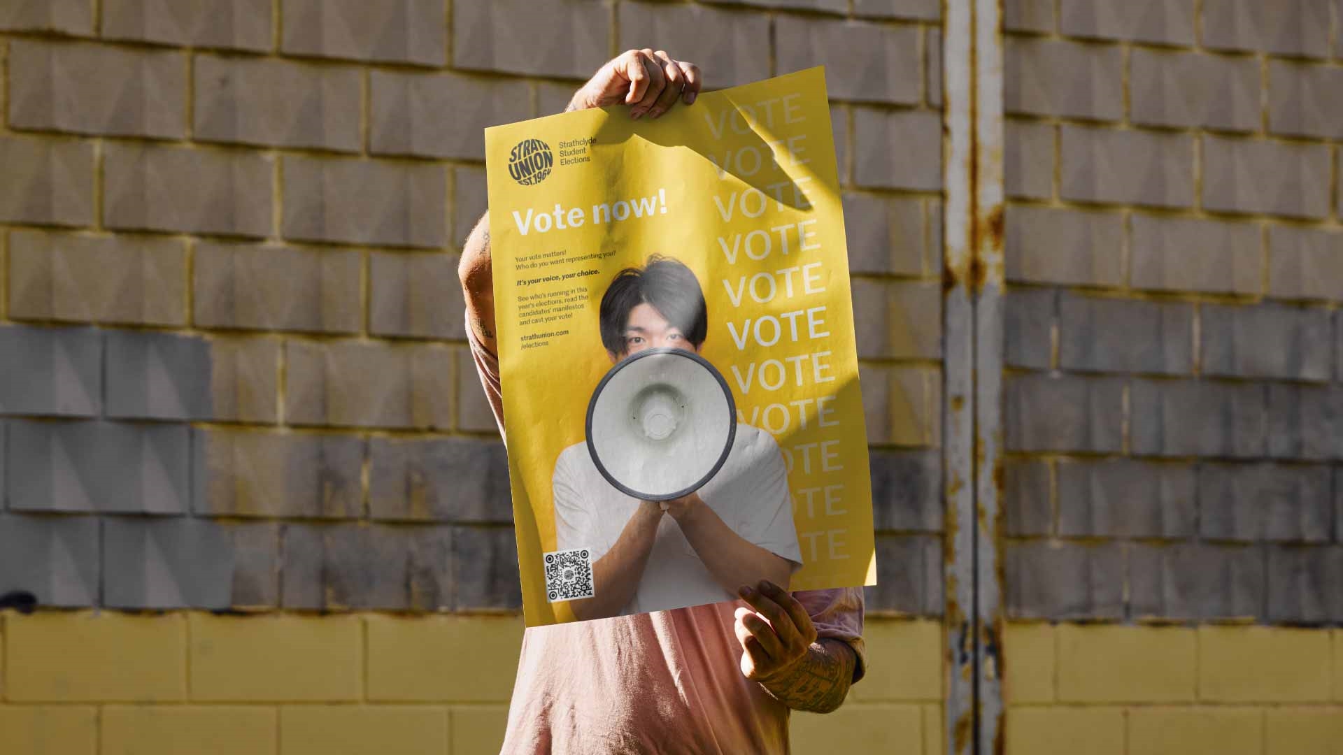 Person holding up Strath Union "Vote" poster in front of their face.