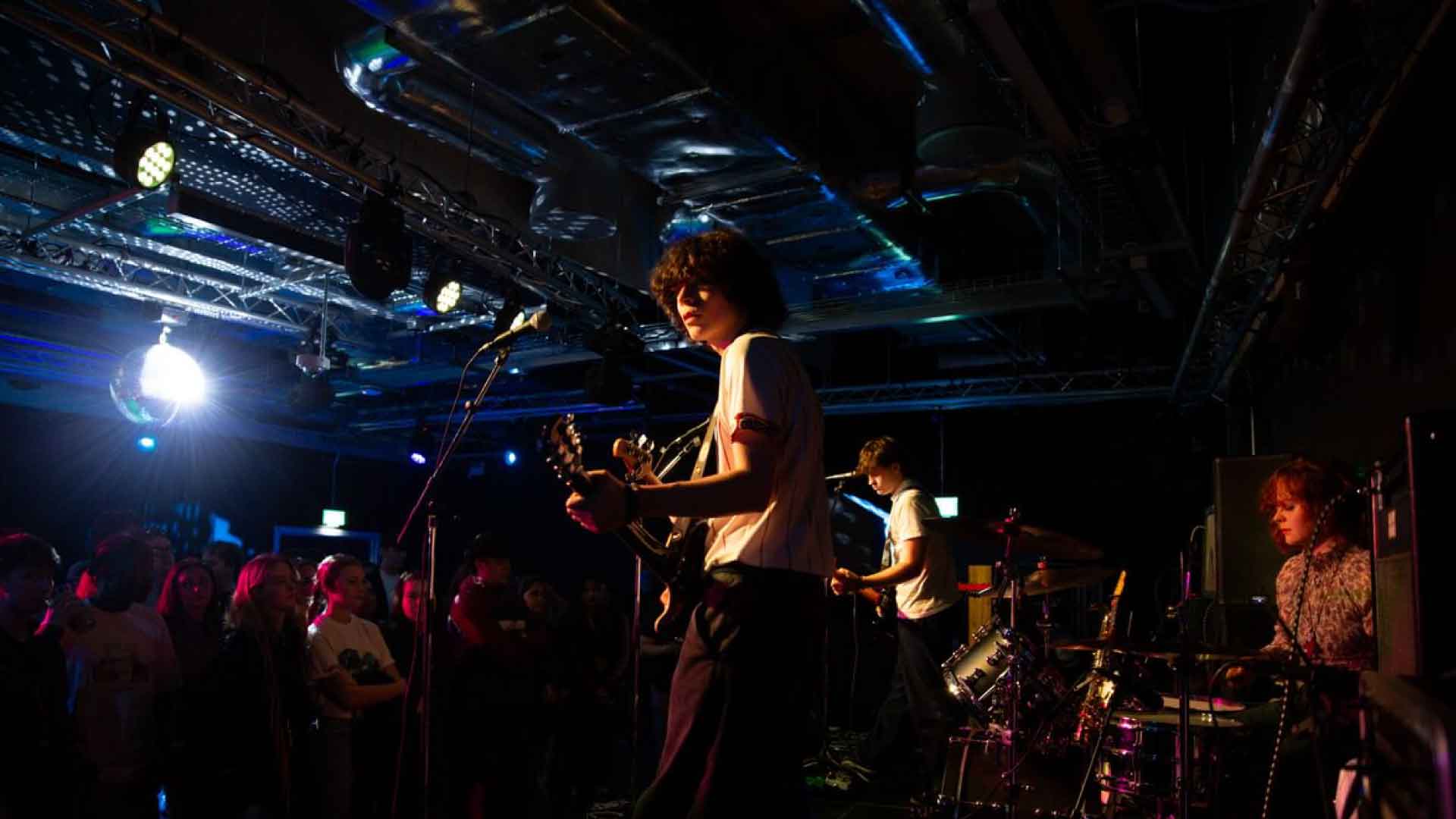Band performing in The Venue to a crowd of students.