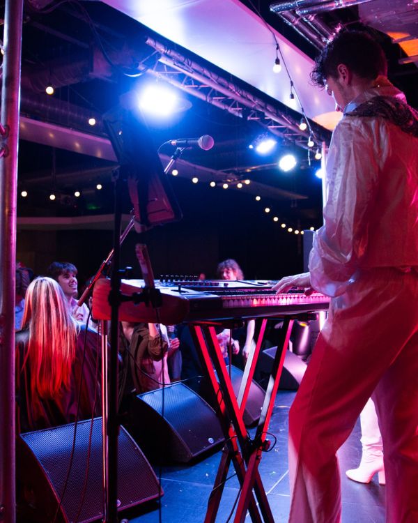 Keyboard player on stage in front of crowd.