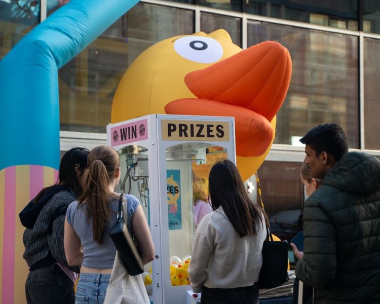 Claw machine sitting in front of inflatable duck.