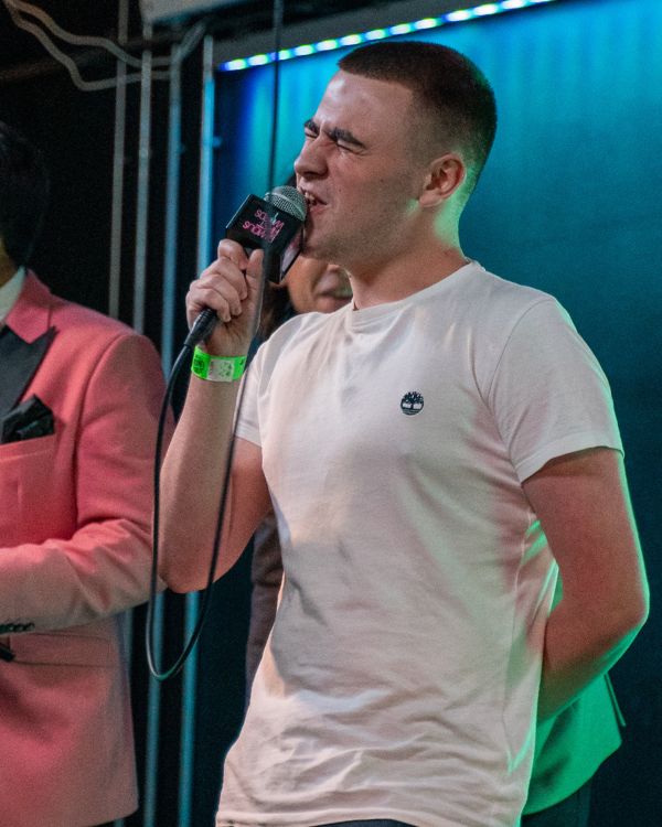 Student singing into microphone on stage.