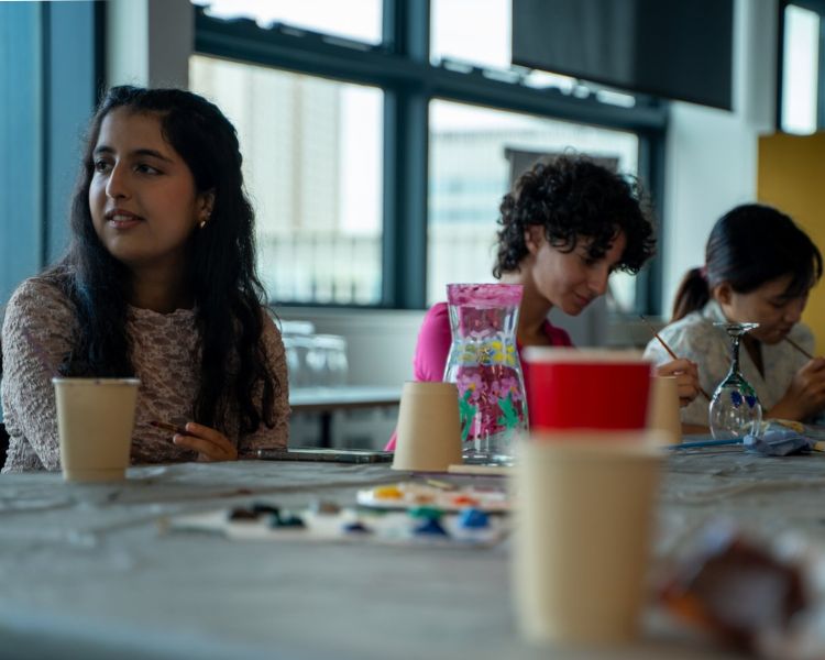 Students painting glasses at workshop.