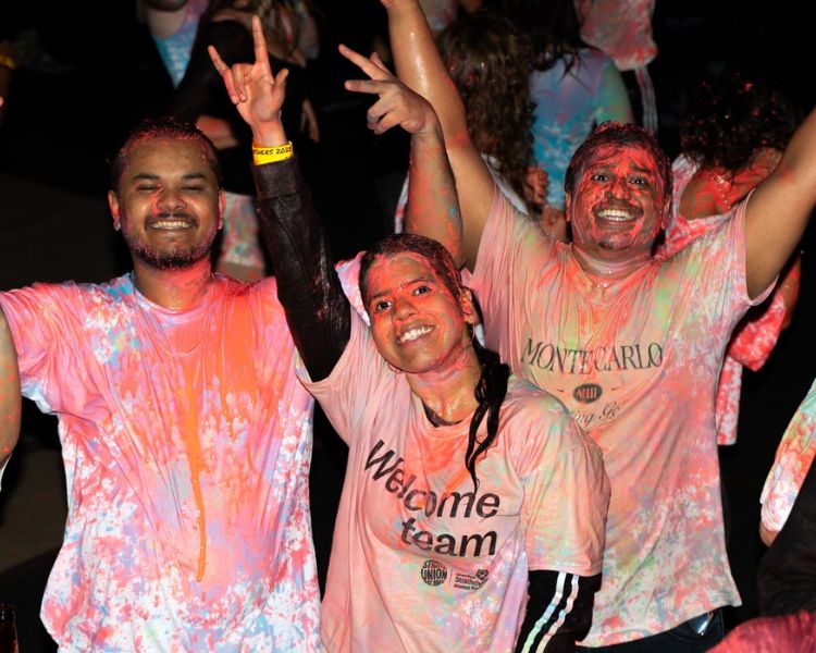Students posing to camera during paint party wearing pink t-shirts.