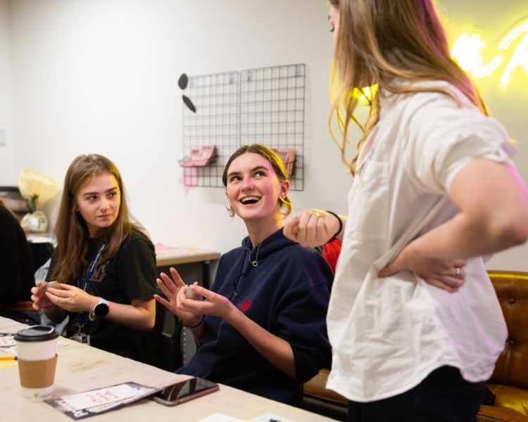 Two students chatting with instructor at pottery class.