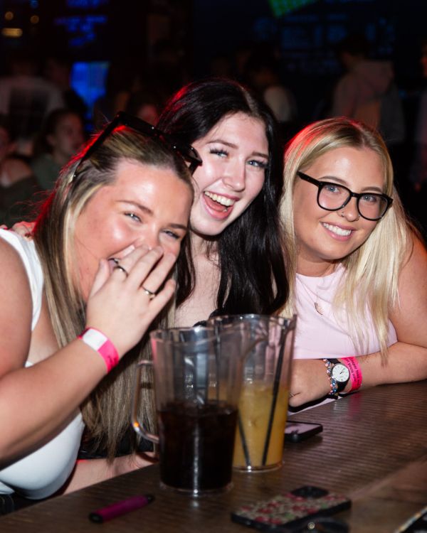 Three students laughing together at event.