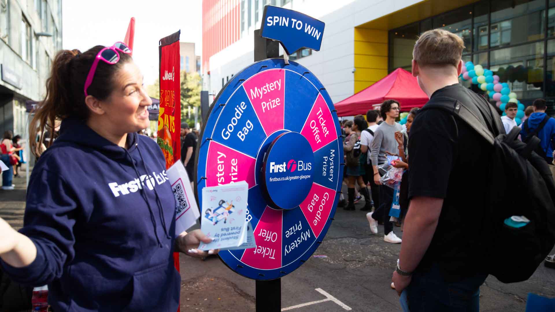 First Bus promoter standing in front of Spin to Win prizes wheel on Richmond Street