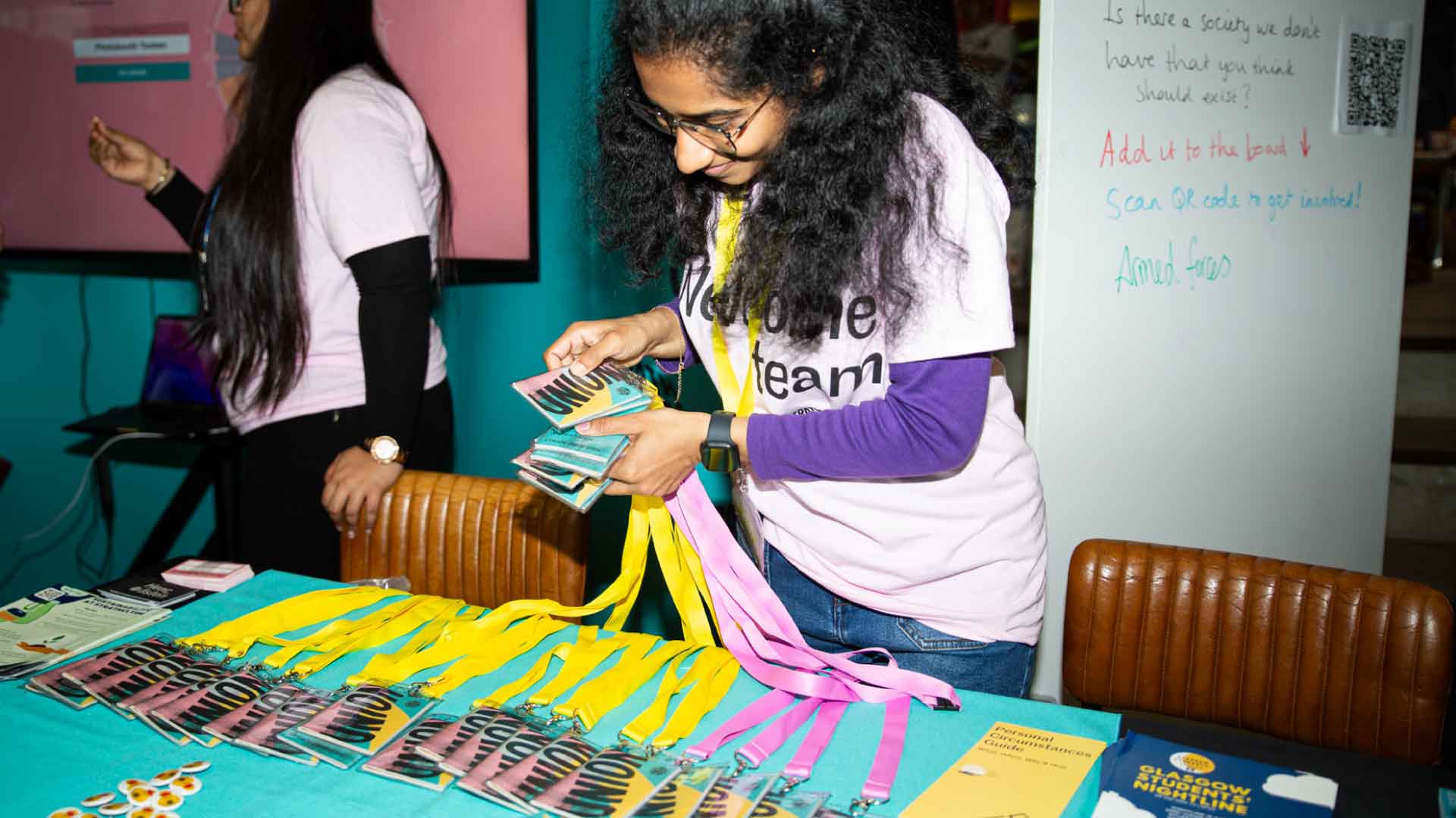 Welcome Team volunteer organising Strath Union booklets on a stall table.