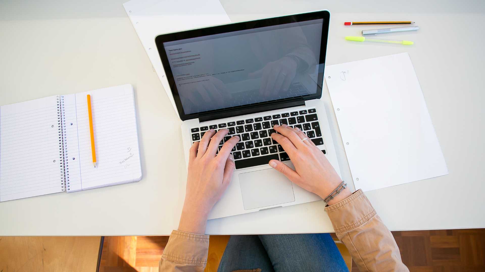 A person typing on laptop keyboard at a desk.