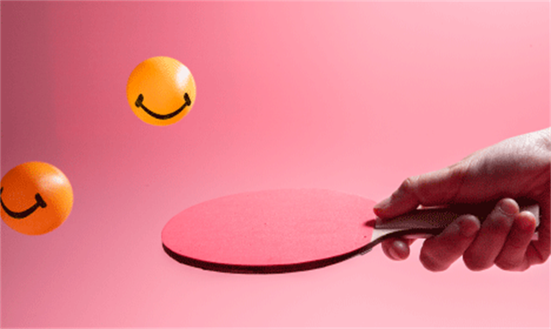A person holding a table tennis bat against a pink backdrop