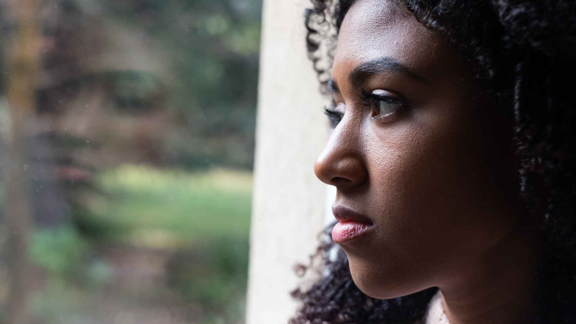 Person looking out of window with a pensive expression