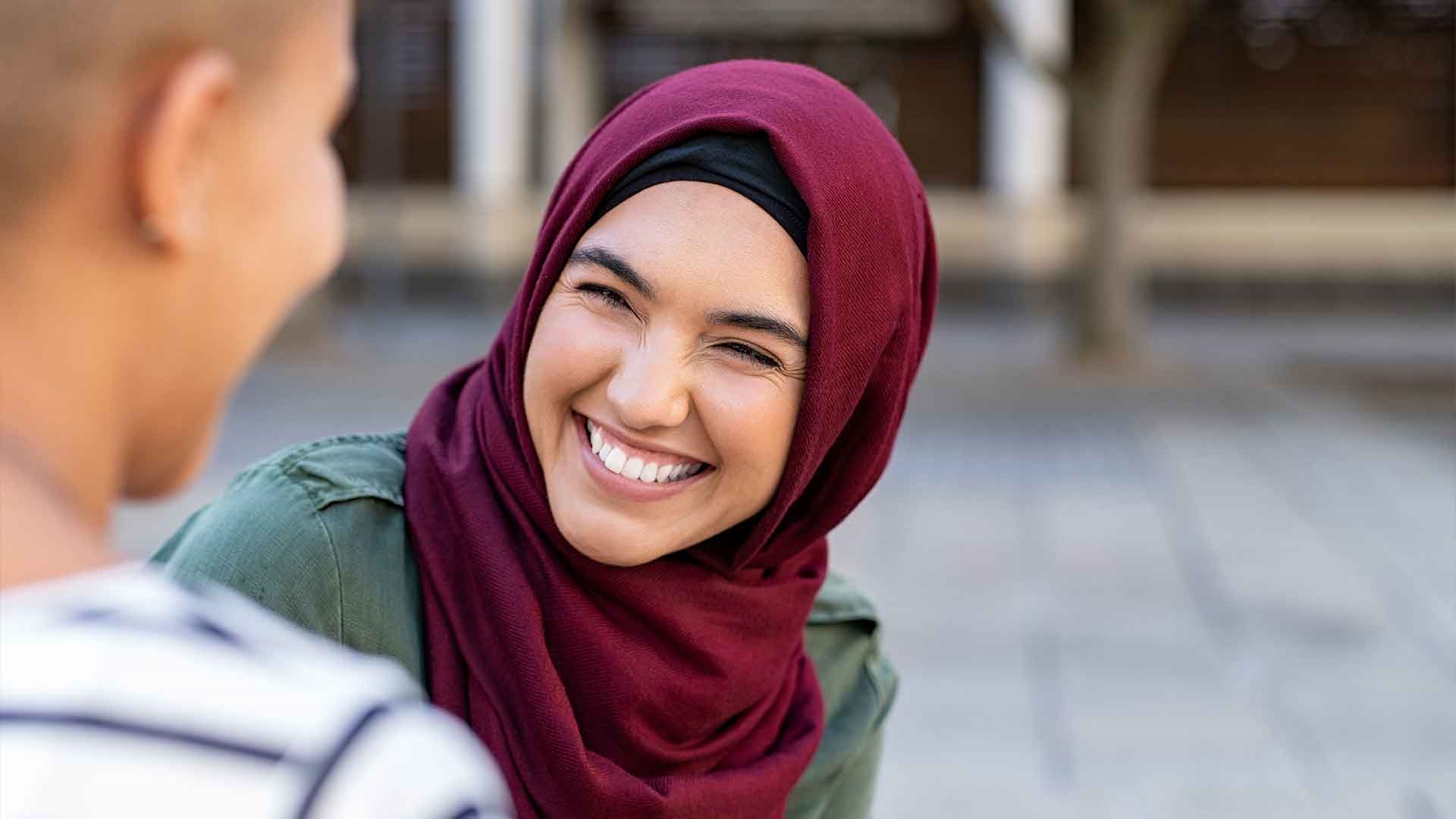A person wearing a hijab and smiling at their friend