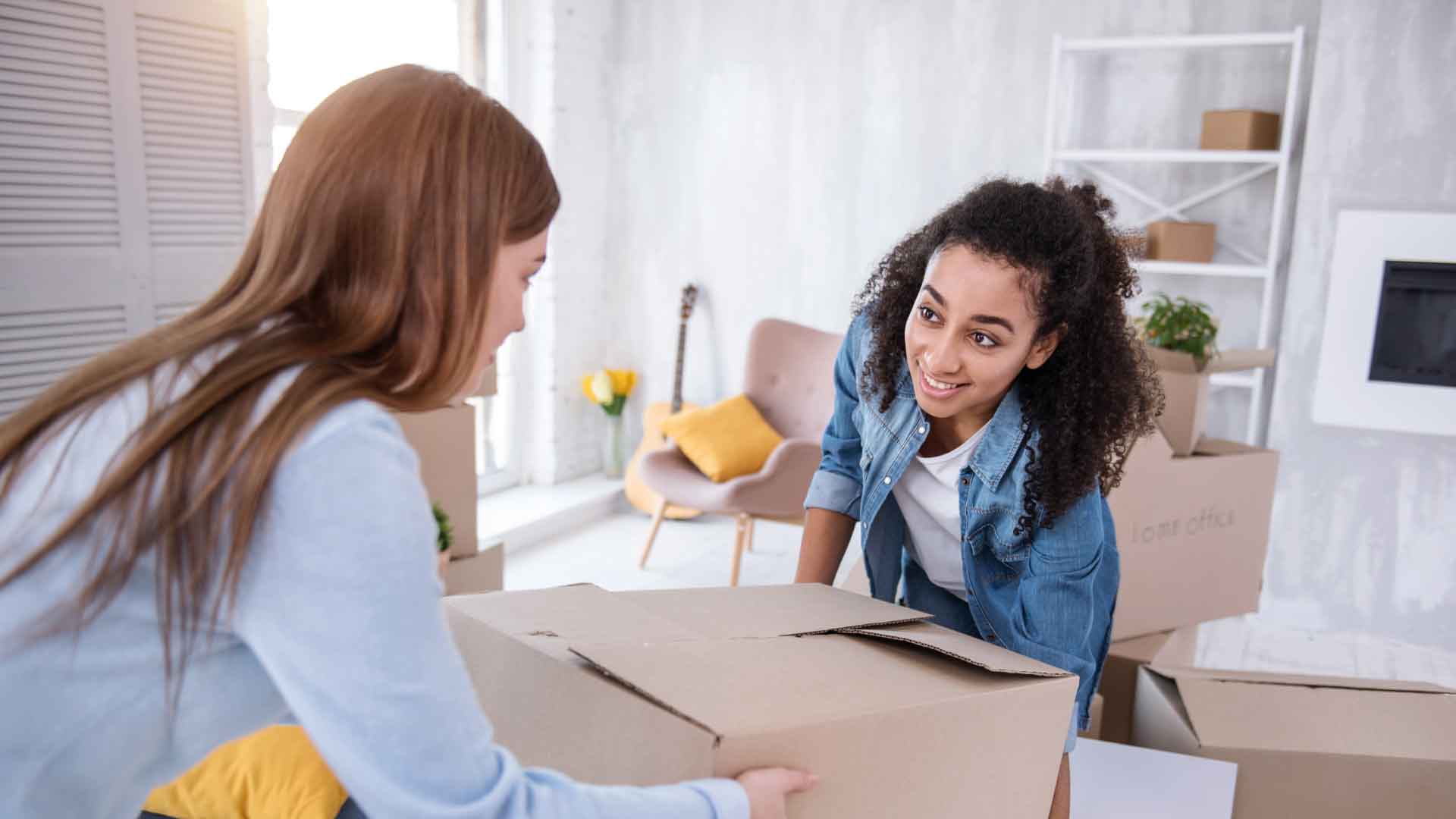 Two people moving boxes into flat