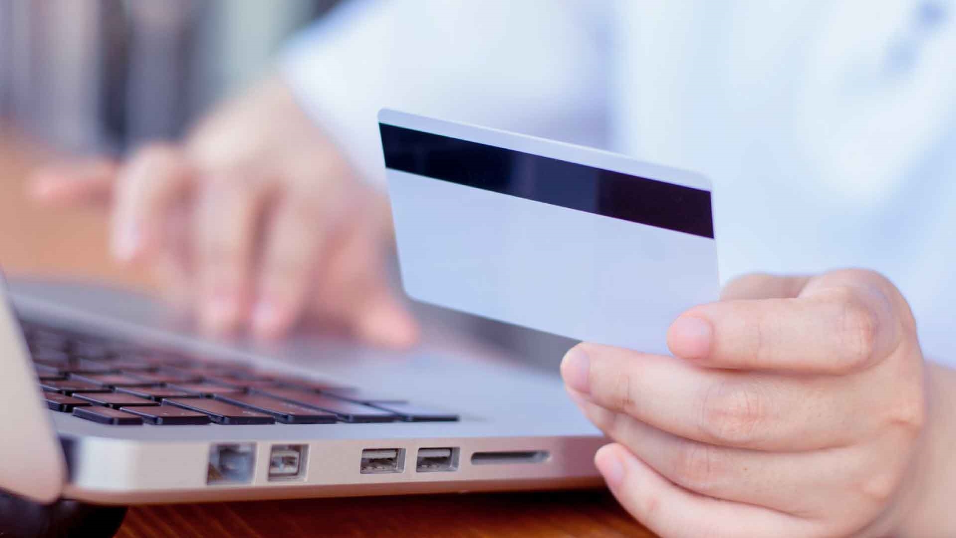 Person using debit card details on laptop