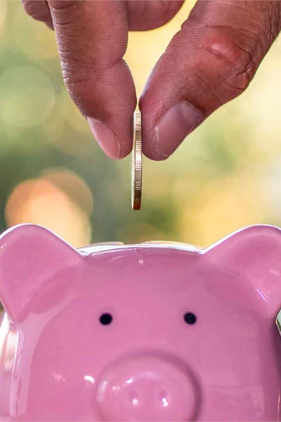 Hand placing coin into piggy bank