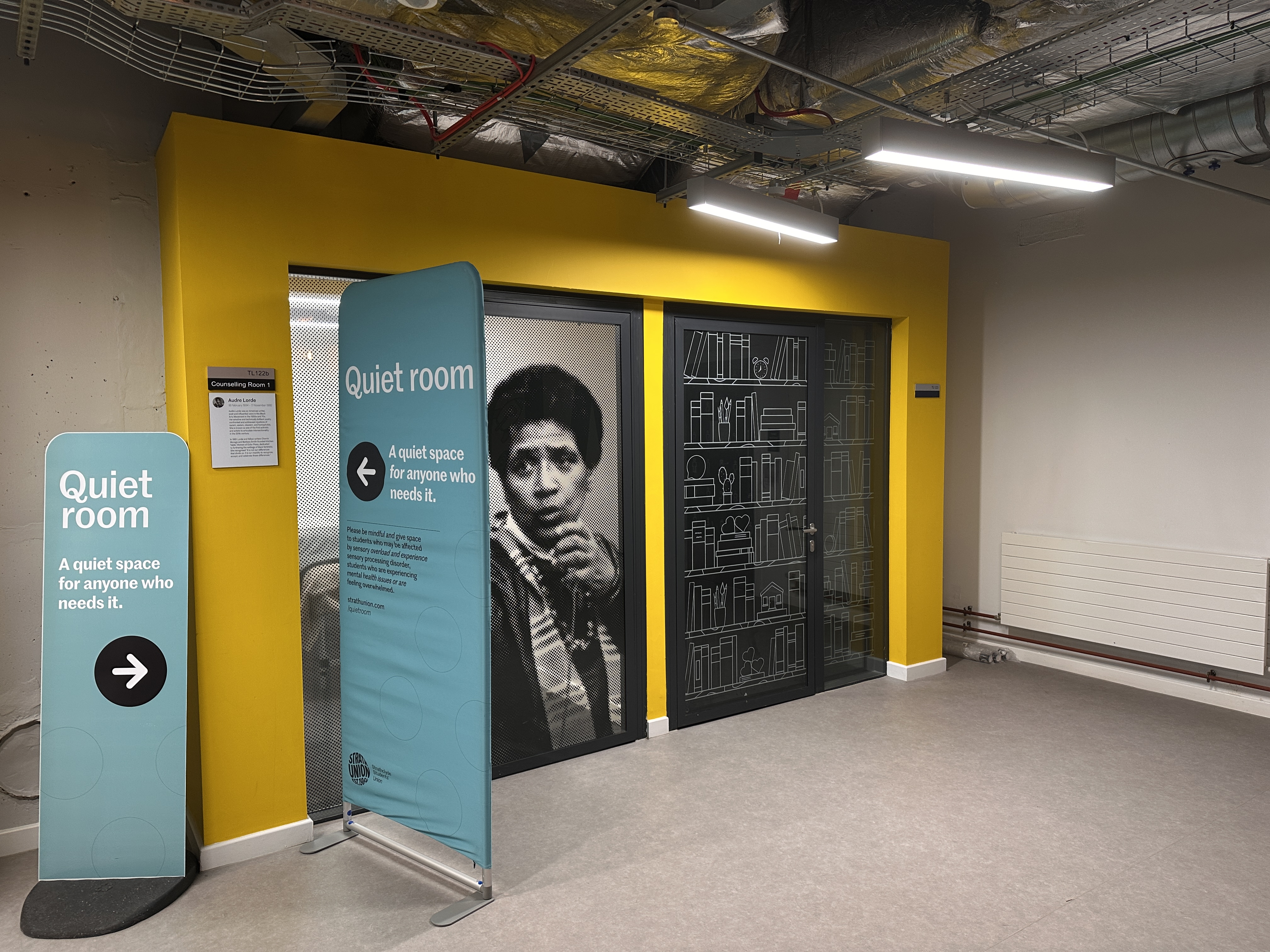 Wide shot of the entrance to the Quiet Room including an image of Audre Lorde on door.