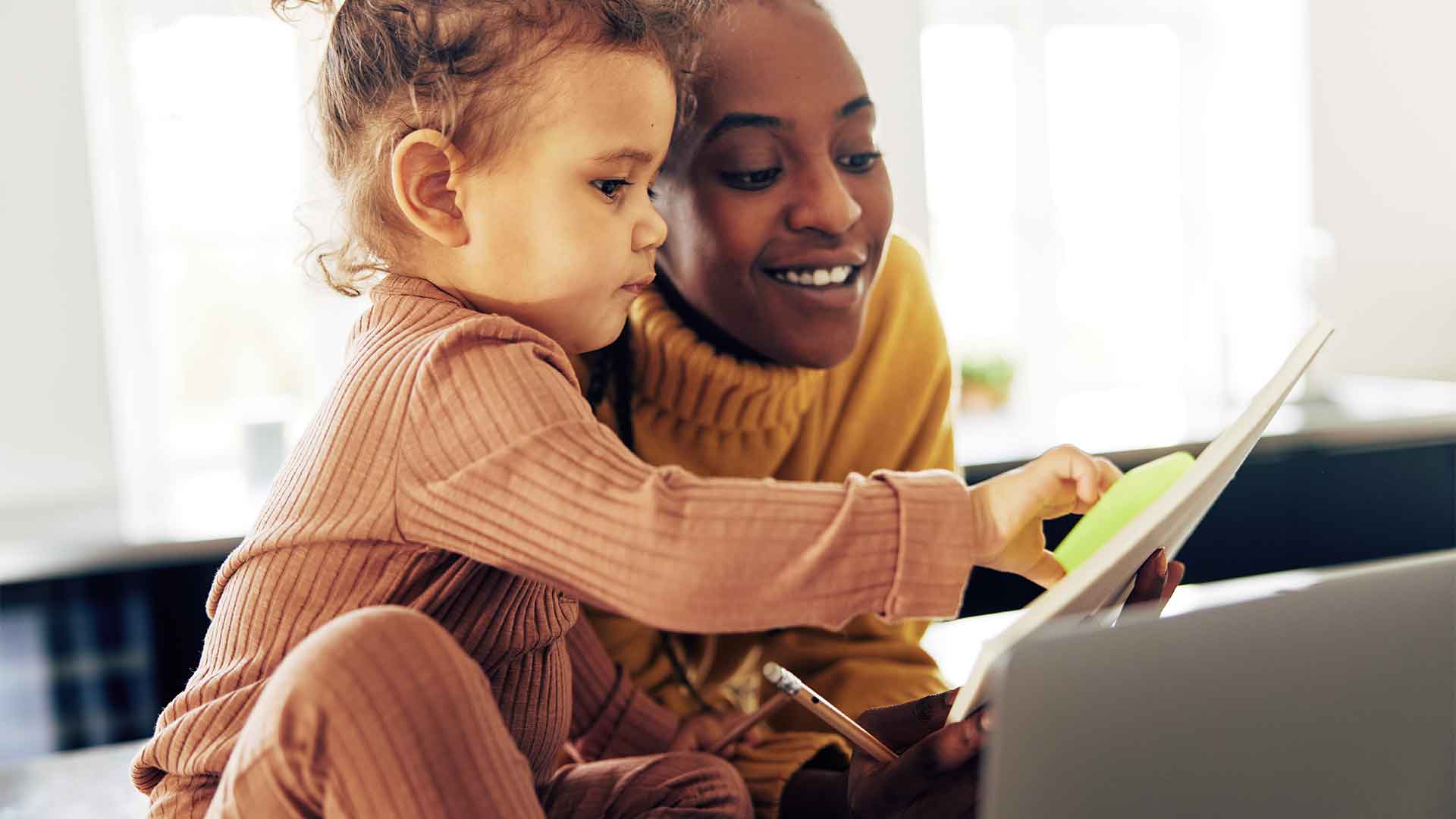 A young student parent sat with their toddler and laughing