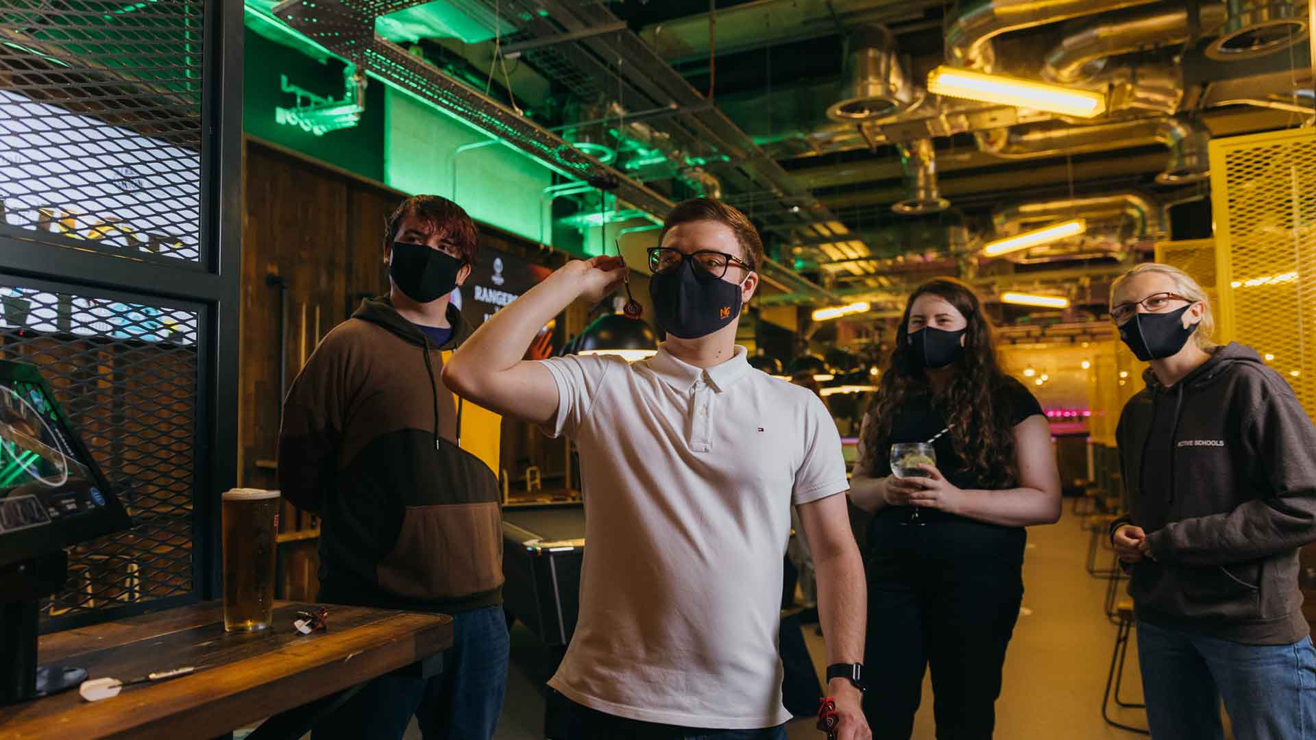 Students wearing masks and throwing darts at a dartboard