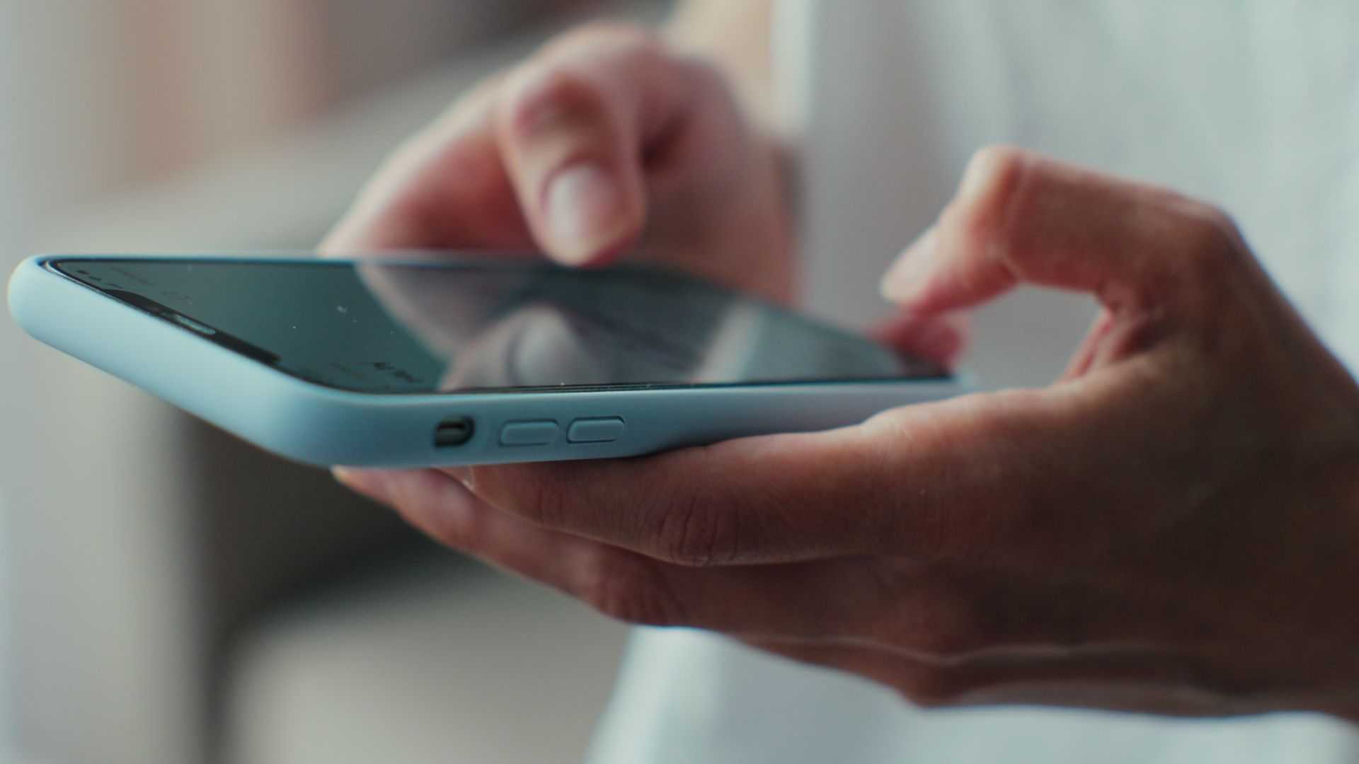 Person using smartphone with both hands typing.