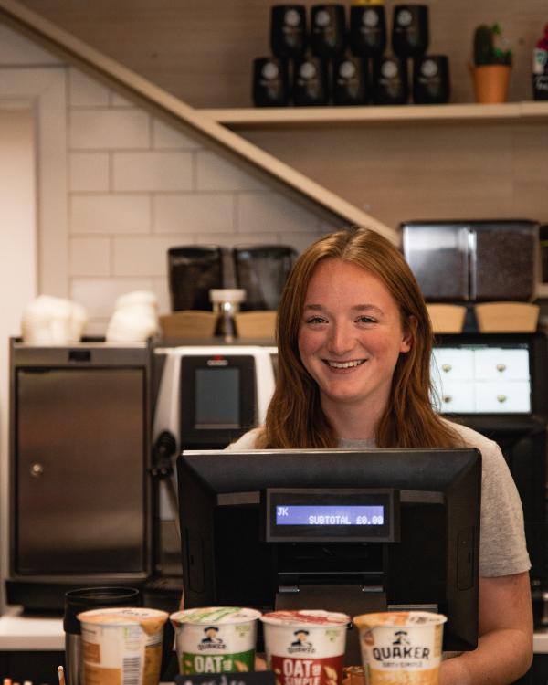 A person ordering coffee, with hanging plants above them