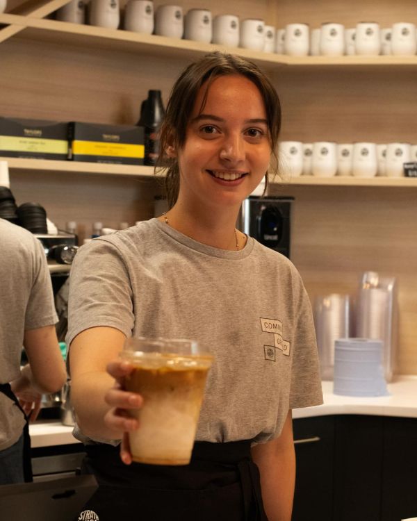 A person ordering coffee, with hanging plants above them