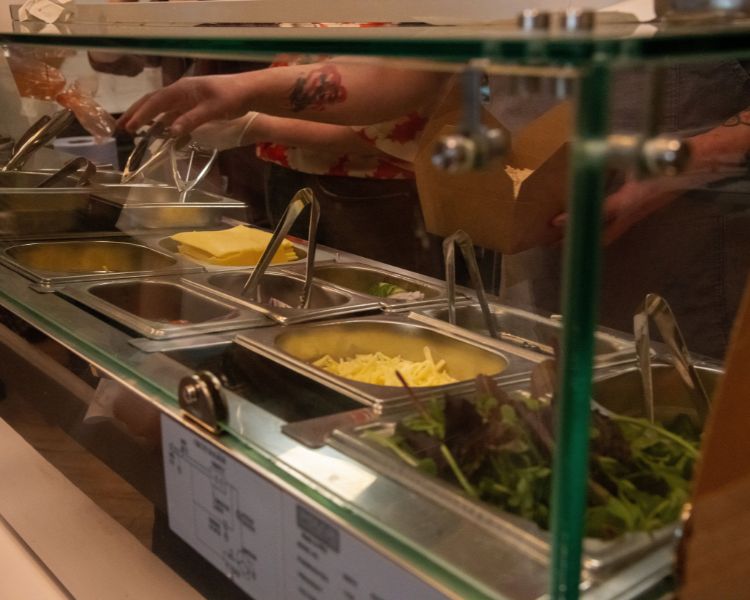 Salad bar with ingredients stored in metal containers.