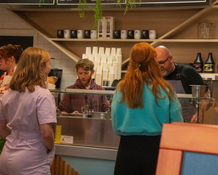 Staff serving customers from the salad bar.