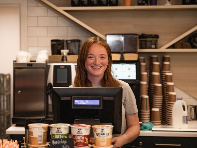 Staff serving customers as till in front of coffee machine