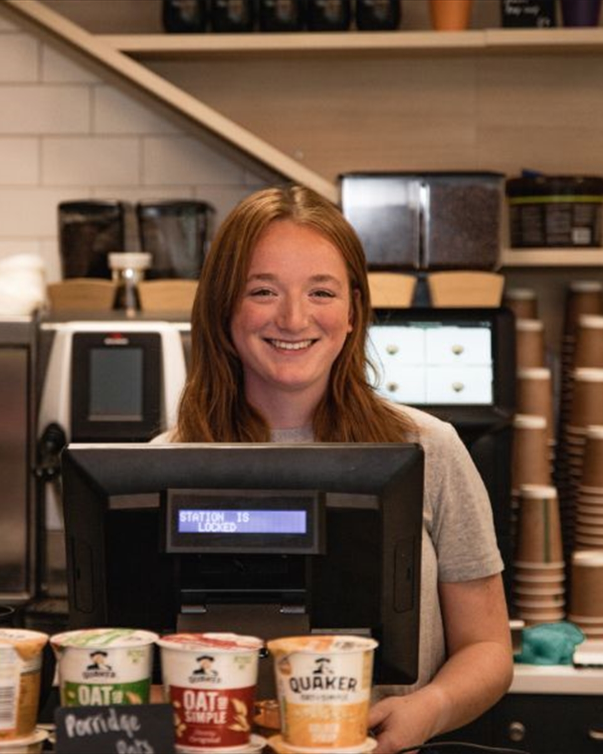 Staff member smiling and serving at till in Common Ground
