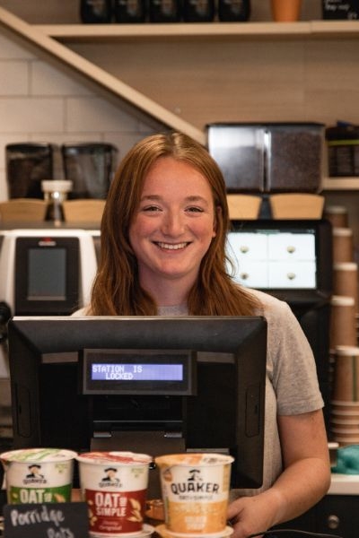 Staff member smiling and serving at till in Common Ground