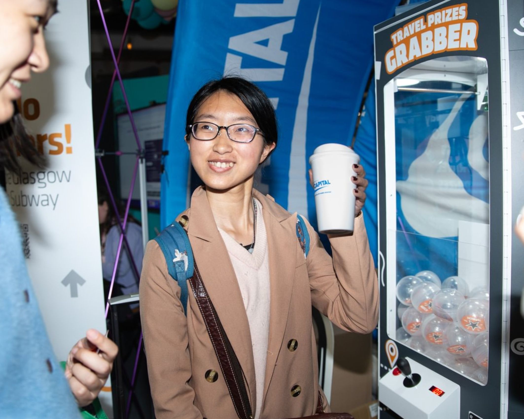 Student holding up branded keep cup won in claw machine game.