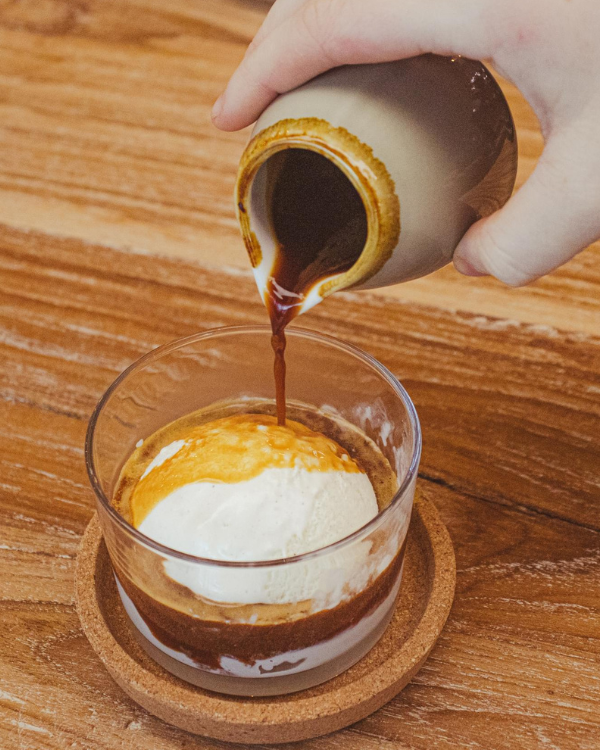 A barista sliding a Roasters cup across the checkout