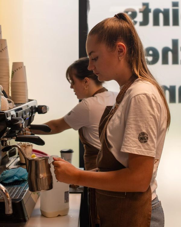 Two baristas making coffee at Roasters.