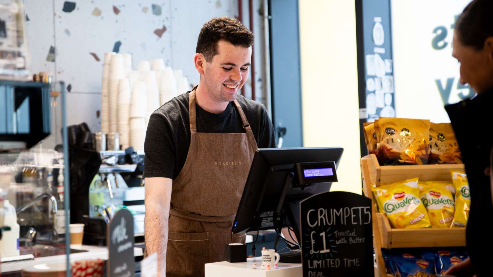 Roasters staff member serving coffee at till