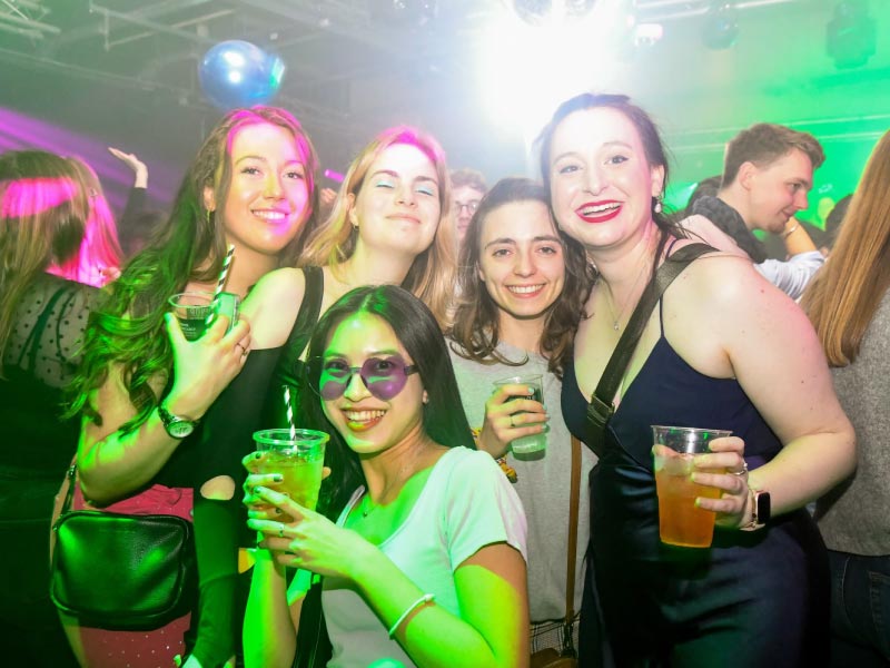 Group of Strathclyde students in The Venue, smiling, holding drinks.