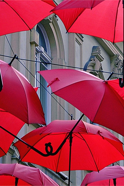Series of open red umbrellas in the sky.