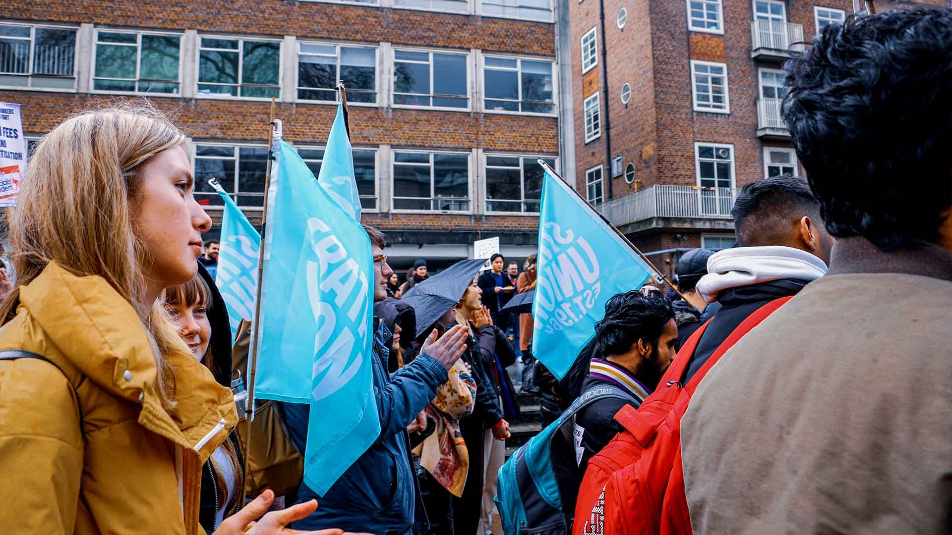 Students walking through Glasgow with blue flags with the Strath Union logo on