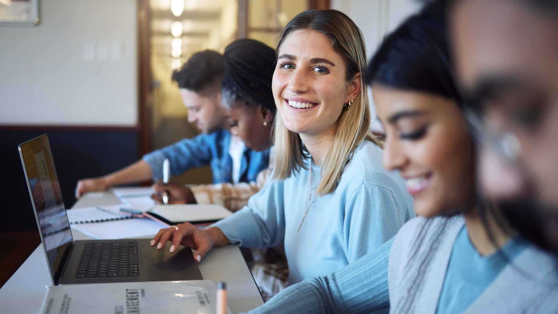 Students studying with laptops and books.
