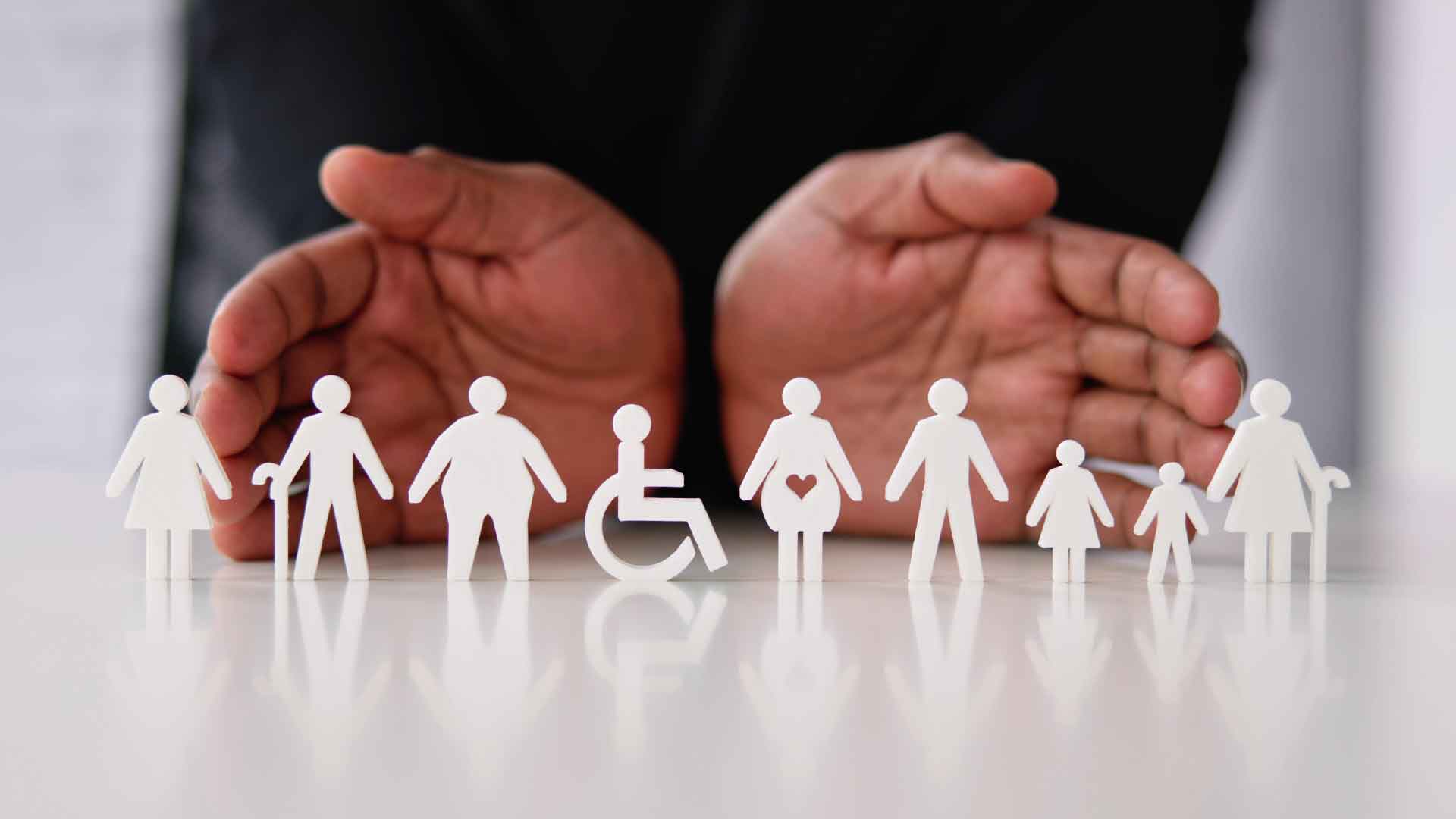 Hands cradling paper figures of a variety of people.