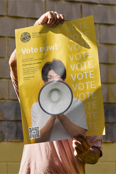 Person holding up Strath Union "Vote" poster in front of their face.