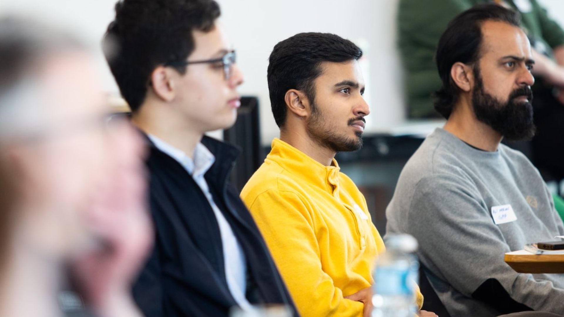 Three students sitting at a table, listening to a presentation at Strath Reps Day.