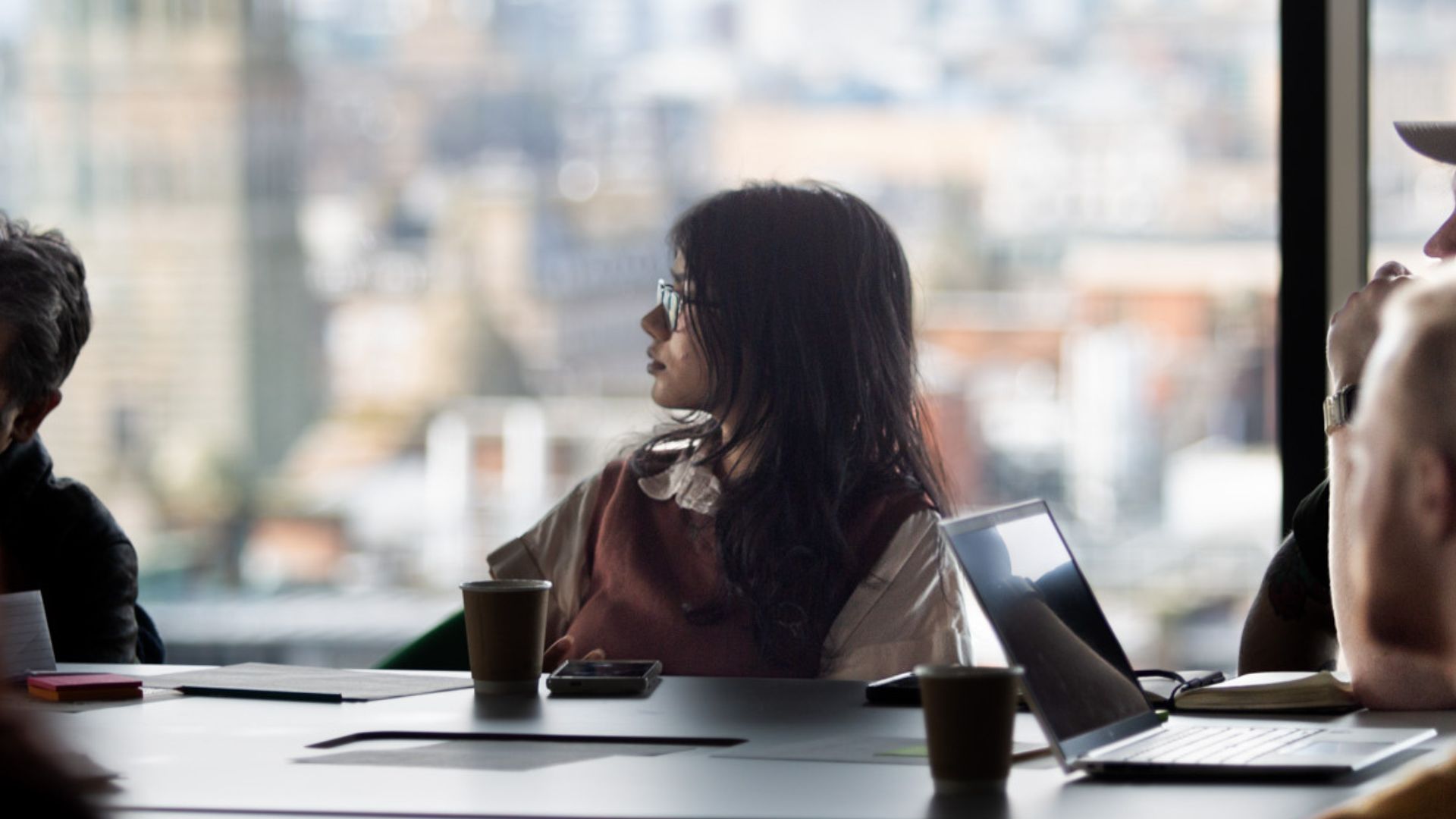 Student sitting at table in front of large window watching a presenter