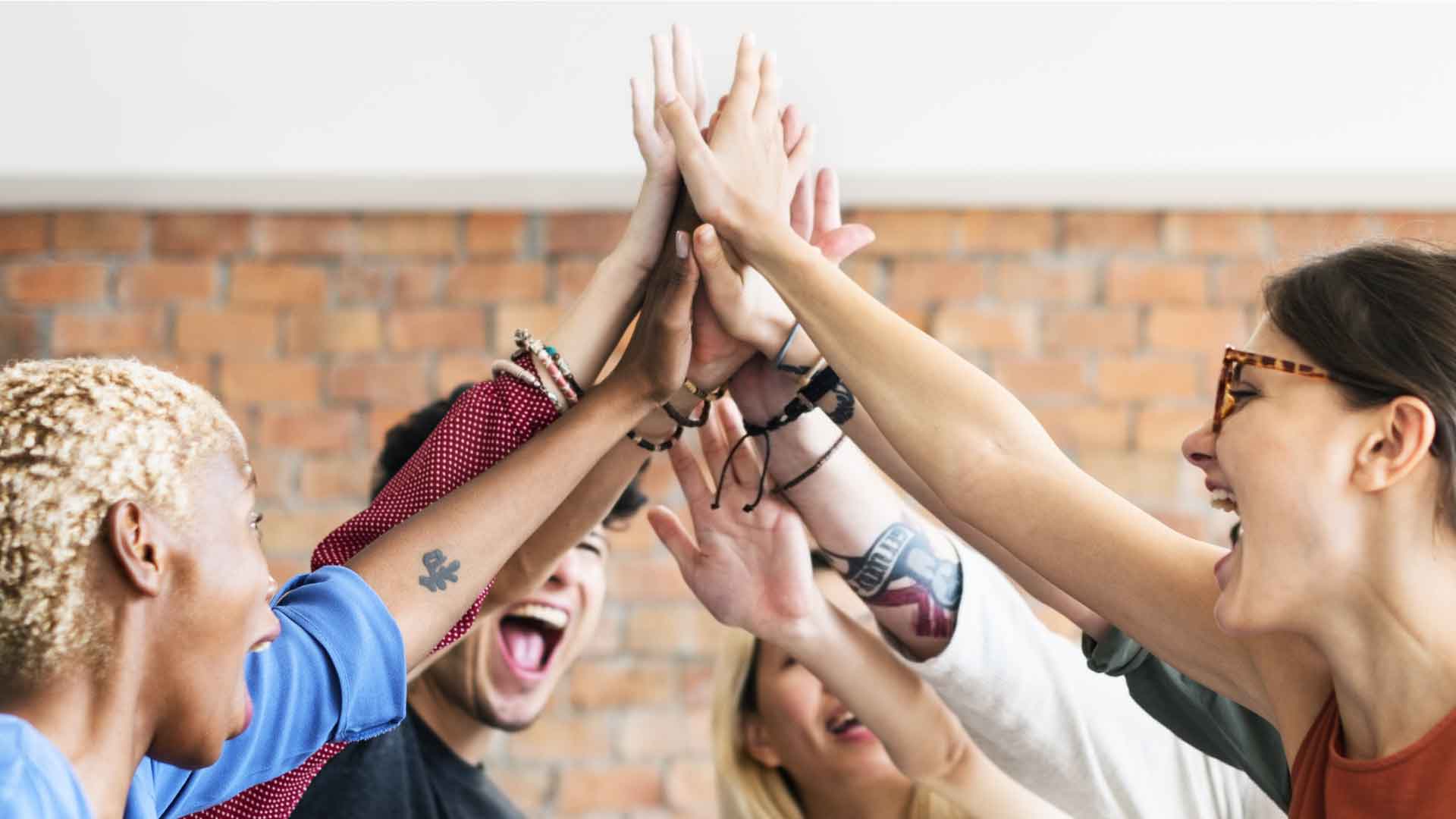 Group of happy people high-fiving each other.